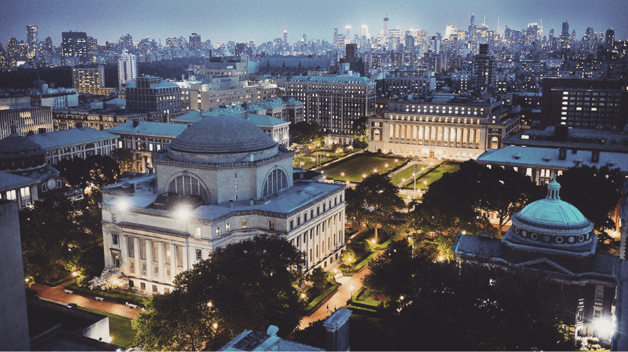 Aerial view of the Columbia University campus at night with view of New York City skyscraper off in the distance..