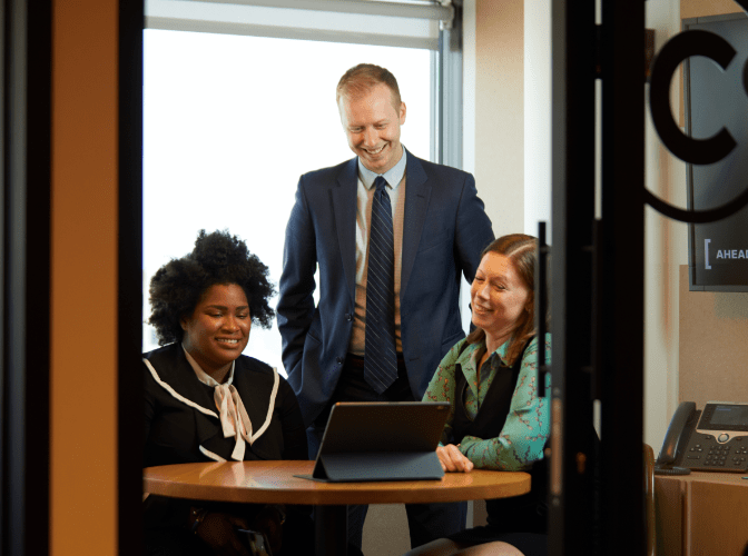 Three AB employees sitting around a table looking at a laptop screen