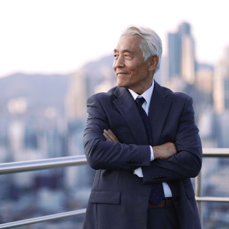 Asian man in business suit gazing off into the distance with skyscrapers as the backdrop