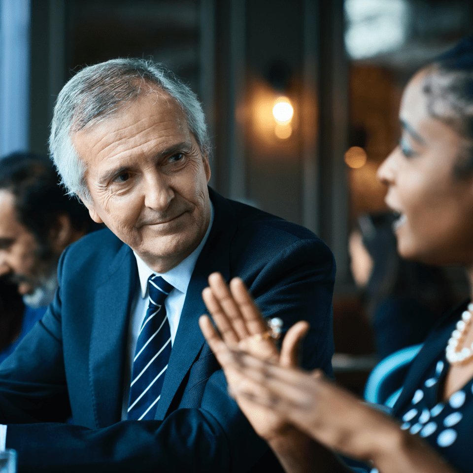 A Caucasian man with gray hair and a black women deep in conversation 