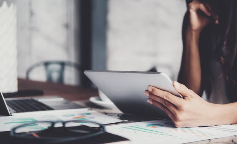 Women looking at tablet in home office, only hands can be seen