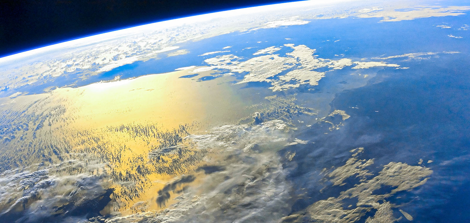 Sunlight glints off the ocean on the Earth’s horizon viewed from space.