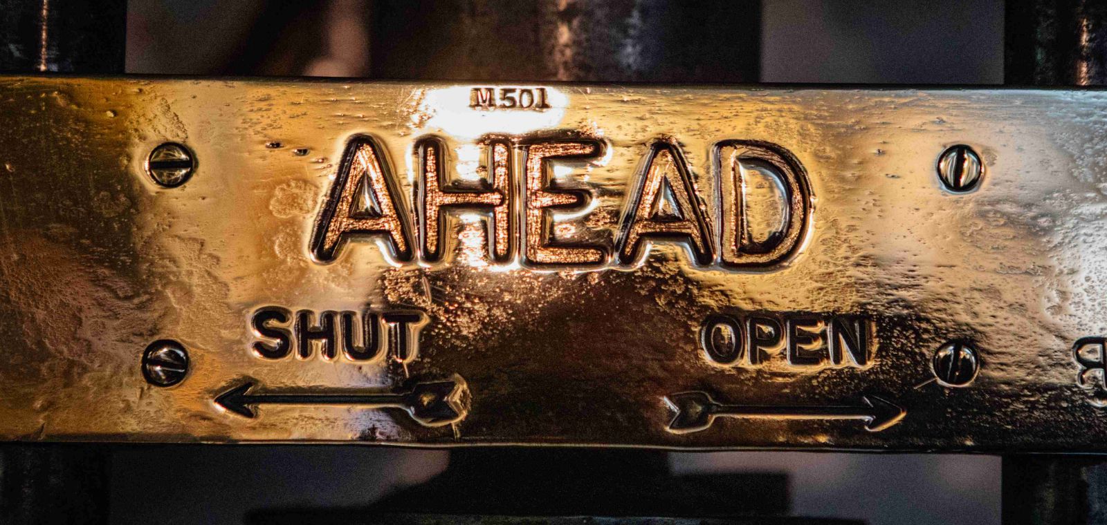 A bronze placard signifies the throttle options of shut or open on a steam engine.